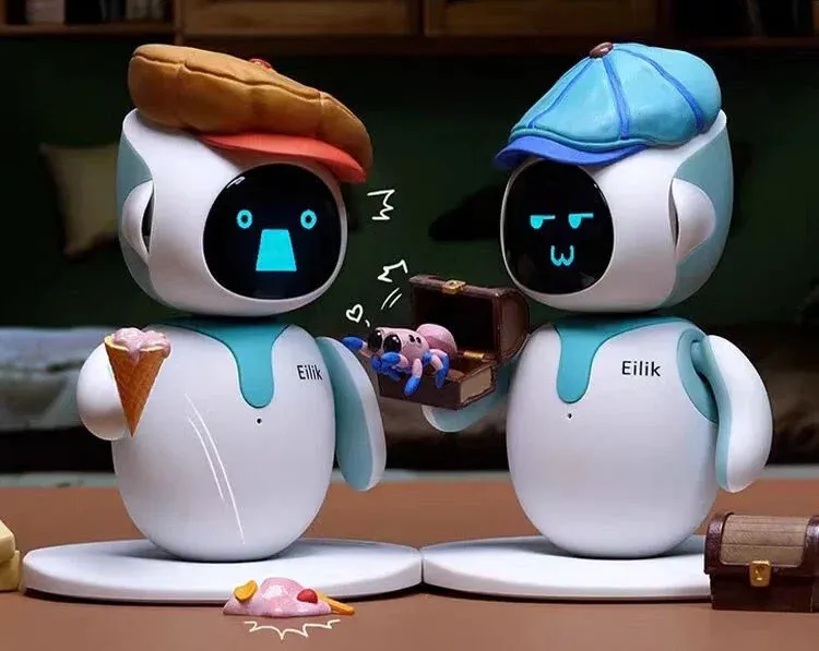 Two Eilik robots with glowing faces interacting in a green play area